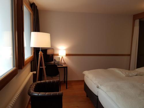 a bedroom with a bed and a desk and a lamp at East West Hotel Basel in Basel