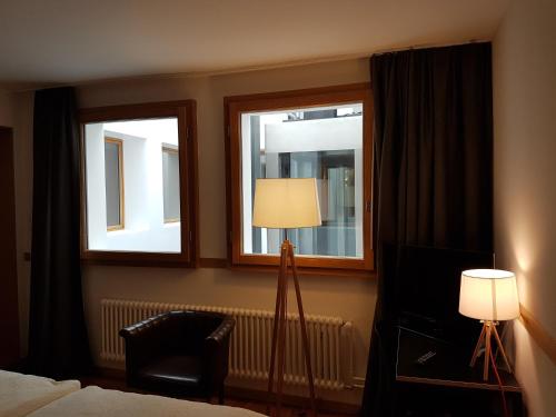 a bedroom with two windows and a lamp and a chair at East West Hotel Basel in Basel