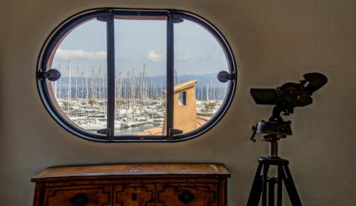 une vue d'un port à travers une fenêtre ronde avec une caméra dans l'établissement Porquerolles Island architectural seaview, à Hyères