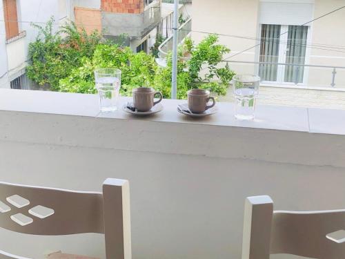 una mesa con dos tazas y dos vasos en un balcón en Vangert Apartment, en Berat