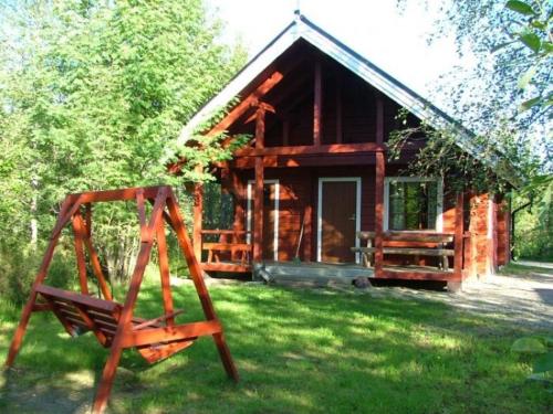 una cabaña de madera con un columpio delante de ella en Loma Rinteelä, en Suonenvaara