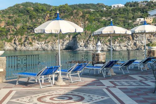 a group of chairs and umbrellas next to the water at Hotel Terme Tritone Resort & Spa in Ischia
