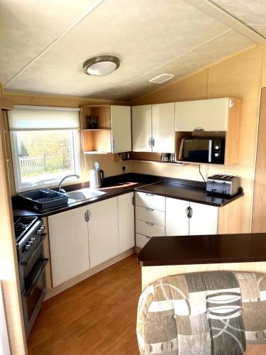 a kitchen with white cabinets and a black counter top at Spacious 8-Berth Caravan at Unity Beach Resort in Brean