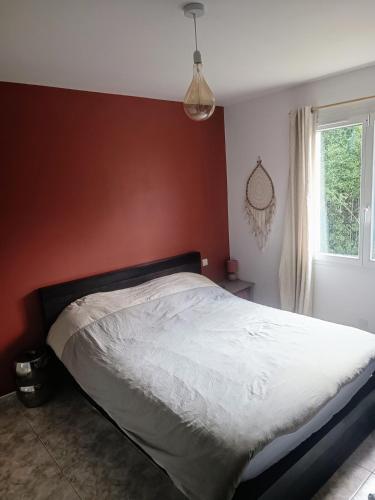 Ce lit se trouve dans une chambre dotée d'un mur rouge. dans l'établissement Familly house with pool, à Caux
