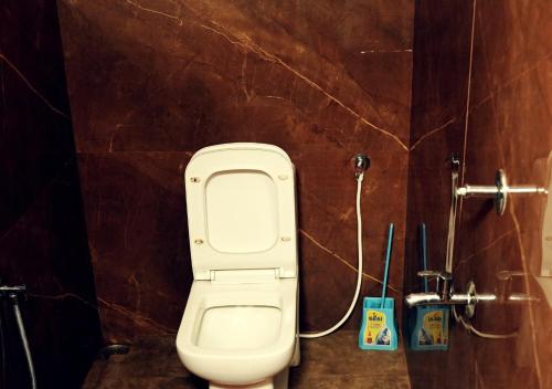 a bathroom with a white toilet in a brown wall at Vintage Vista in Lakkidi