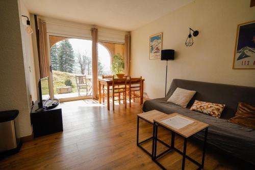 un salon avec un canapé et une table dans l'établissement Appartement très calme 2 chambres avec parking et jardin privé sur les hauteurs de Briançon, à Briançon