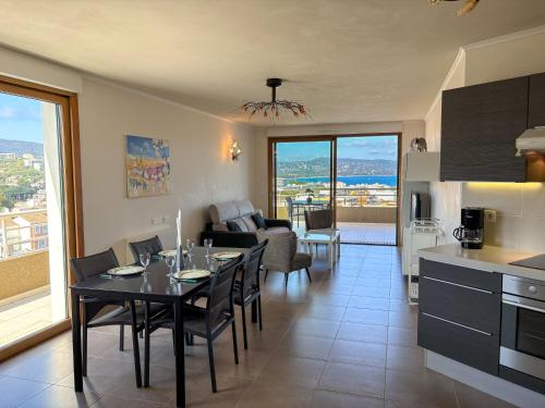une cuisine et un salon avec une table et des chaises dans l'établissement Azura - Appartement Climatisé 2 Chambres Terrasse Vue Mer avec Parking Privé Gratuit, à Cavalaire-sur-Mer