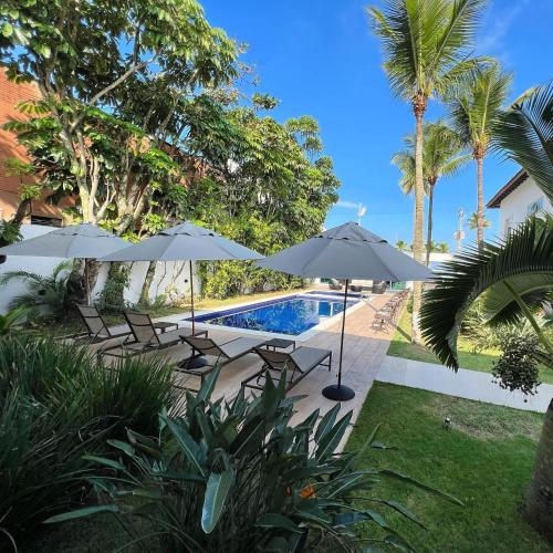 a swimming pool with umbrellas and chairs next to a resort at Makai Hotel Boutique - Frente Mar in Guarujá