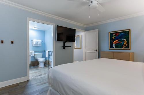 a bedroom with a white bed and a bathroom at Crane's Beach House Boutique Hotel & Luxury Villas in Delray Beach