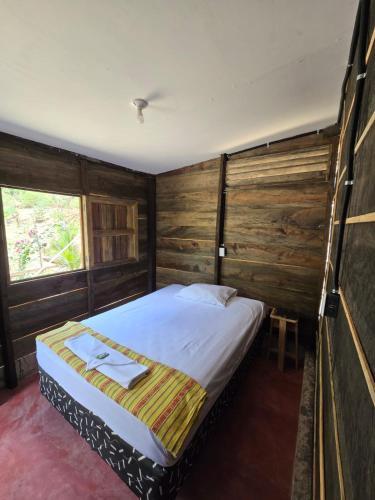 a bedroom with a large bed with wooden walls at Rustik Hostal in Lanquín