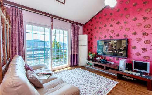 a living room with a couch and a tv at Spa Pension Basso in Sokcho
