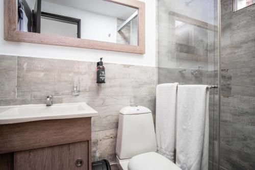 a bathroom with a toilet and a sink and a mirror at Azor Hotel Cali Versalles in Cali