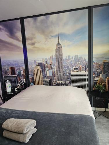 a bed in a room with a view of a city at 1988 NEW YORK Baignoire ilot et video projecteur in Seyssinet-Pariset