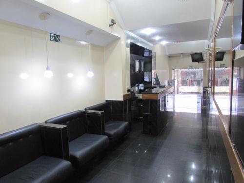 una sala de espera con sofás de cuero negro y un bar en Hotel Plaza Olido, en São Paulo