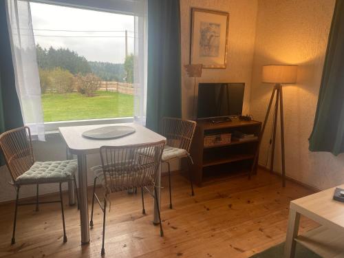 a living room with a table and chairs and a television at Ruhiger und renovierter Bungalow mit großem hundefreundlichem Garten zur Alleinnutzung in Remtengrün