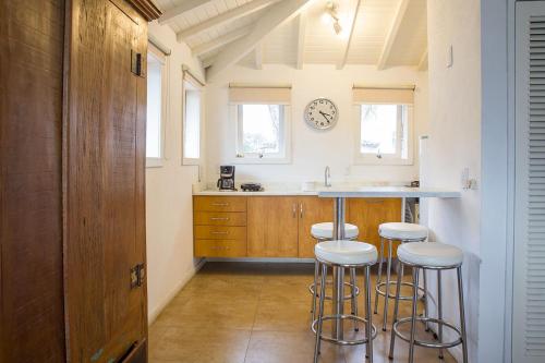 a kitchen with bar stools and a clock on the wall at Passeio das Palmeiras in Búzios