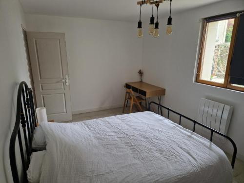 a bedroom with a bed and a desk and a window at Le Pressoir in Turquant