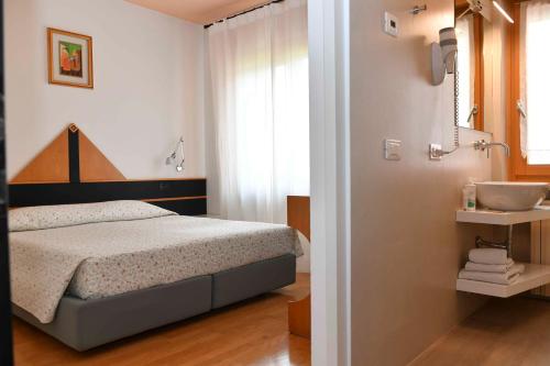 a bedroom with a bed and a bathroom with a sink at Locanda San Lorenzo in Puos dʼAlpago