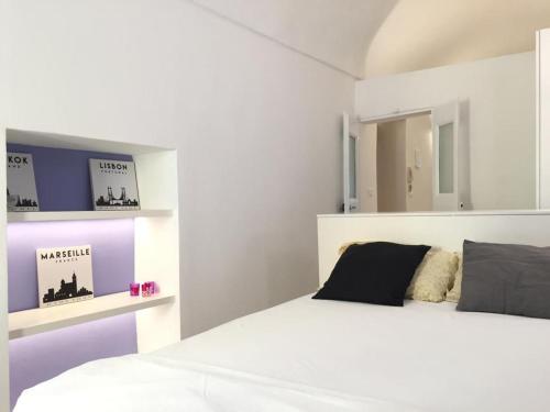 een witte slaapkamer met een bed en een spiegel bij Sole Mio in Sanremo