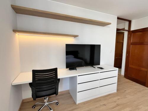 a white desk with a television and a black chair at Sori Apartments in Lima