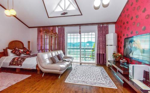 a bedroom with a bed and a tv and a couch at Spa Pension Basso in Sokcho
