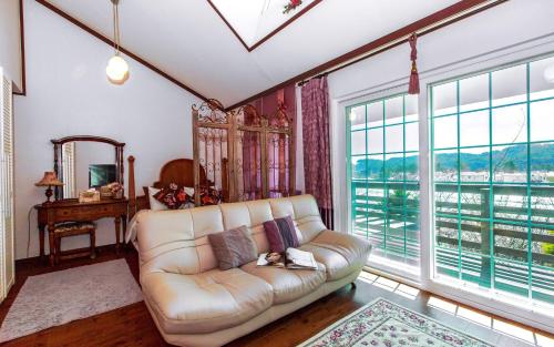 a living room with a couch and large windows at Spa Pension Basso in Sokcho