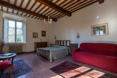 a living room with a red couch and a bed at Il Casale Di Villa Rossi in Lucca