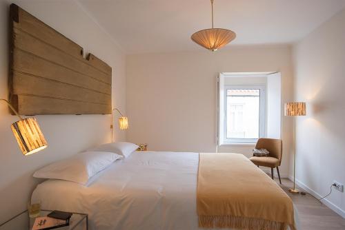 a bedroom with a large white bed and a chair at Vila Marta - Toutinegra in Vila Franca do Campo