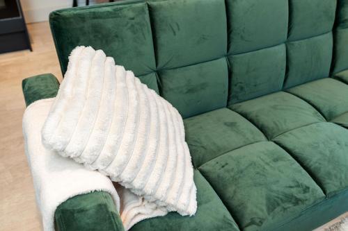 a white blanket sitting on a green couch at Archies Cozy Retreat A Stylish Derby Hideaway in Derby