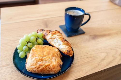 a blue plate with bread and grapes and a cup of coffee at Archies Cozy Retreat A Stylish Derby Hideaway in Derby