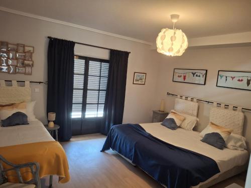a bedroom with two beds and a chandelier at Casa Sampaio e Melo in Gafanha da Nazaré
