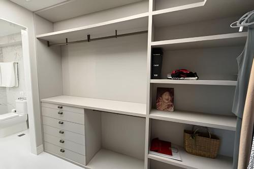 a bathroom with a walk in closet with white shelves at Ed. Premium in Curro Velho