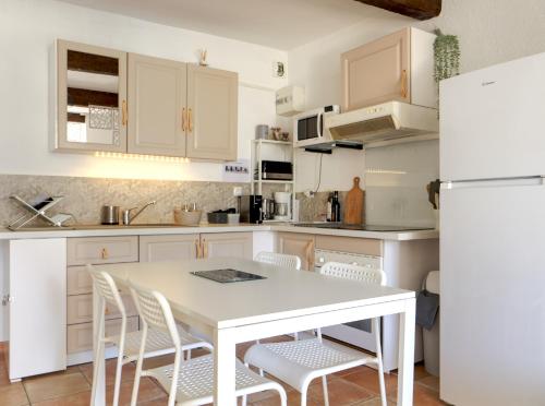 a kitchen with white cabinets and a white table and chairs at Côté Place in Riez