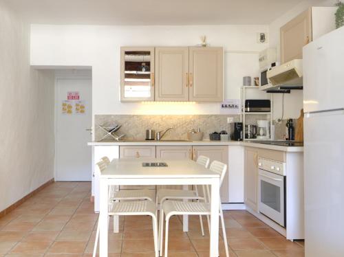 a white kitchen with a white table and chairs at Côté Place in Riez