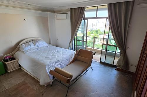 a bedroom with a bed and a chair and a window at Ed. Delta Gardenn in Carmo