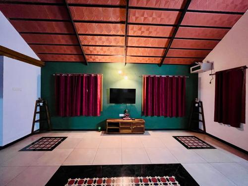 a living room with red curtains and a television at Chettinad Courtyard By Shivalaya Coimbatore in Alāndurai
