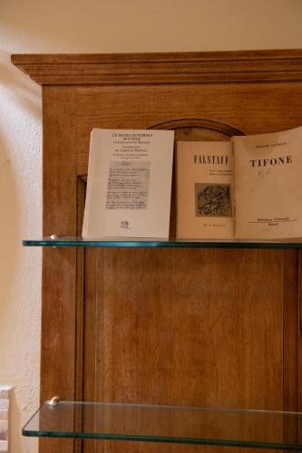 a shelf with books on top of a wooden cabinet at Il Casale Di Villa Rossi in Lucca