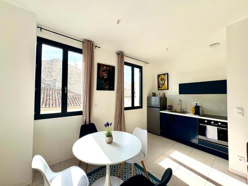 - une cuisine avec une table et des chaises blanches dans la chambre dans l'établissement L'Artelier,T2 centre Nîmes, lit 160, CLIM, à Nîmes