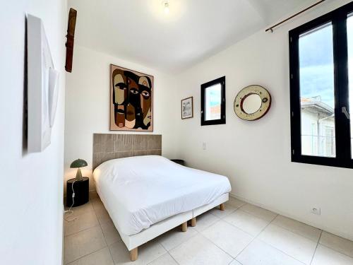 une chambre blanche avec un lit et une fenêtre dans l'établissement L'Escale, T3 CLIM – 6 pers, Nîmes hyper-centre, à Nîmes