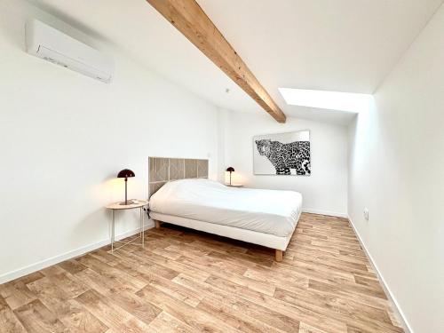 une chambre blanche avec un lit et un parquet dans l'établissement L'Escale, T3 CLIM – 6 pers, Nîmes hyper-centre, à Nîmes