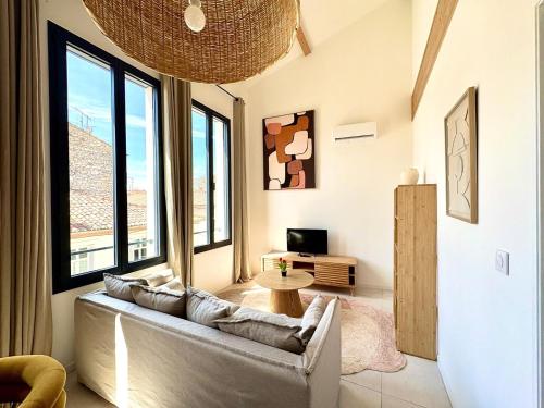 - un salon avec un canapé et de grandes fenêtres dans l'établissement Le Luma, Spacieux T3 – 6 pers, centre Nîmes, CLIM, à Nîmes