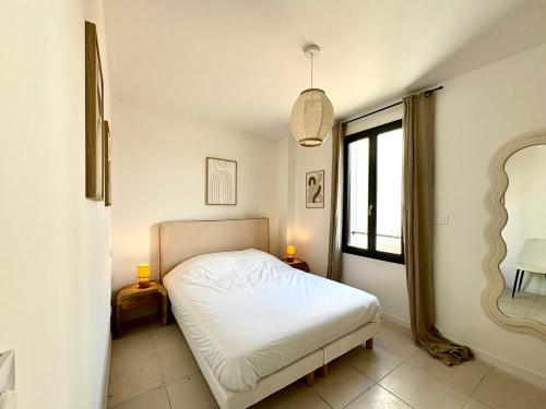 une chambre avec un lit blanc et une fenêtre dans l'établissement Le Luma, Spacieux T3 – 6 pers, centre Nîmes, CLIM, à Nîmes