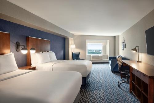 a hotel room with two beds and a desk at Wyndham Grand Fallsview Hotel in Niagara Falls