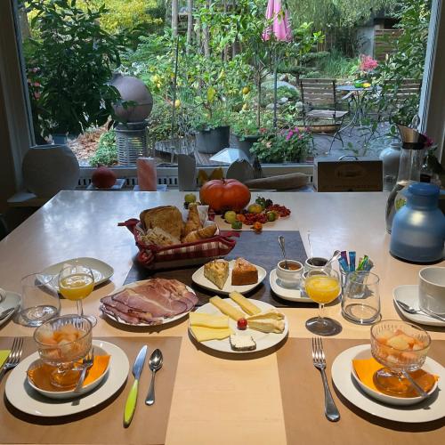 a table topped with plates of food and glasses of orange juice at Le Jardin De La Tuilerie Alsace in Pfastatt