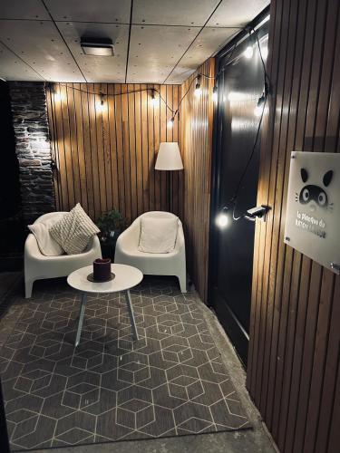 a room with a table and two chairs and a lamp at La planque du raton laveur in Lierneux