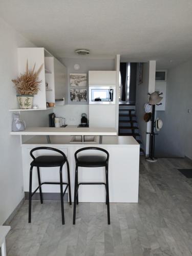 une cuisine avec deux tabourets de bar et un comptoir dans l'établissement Appartement Entre port et mer haut standing, à La Grande Motte