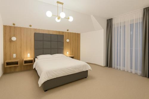 a bedroom with a large white bed and a chandelier at Resort EDEN - domki, pokoje, apartamenty, sauna, jacuzzi in Jastrzębia Góra