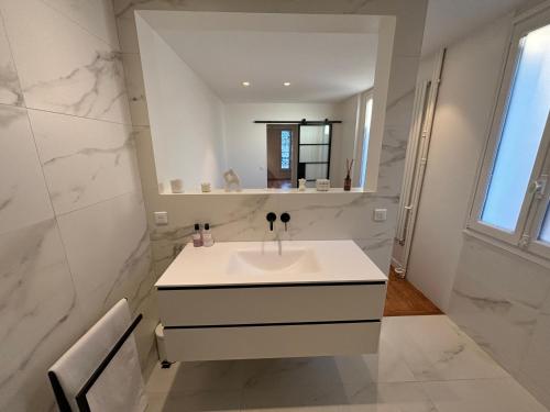 une salle de bain blanche avec un lavabo et un miroir dans l'établissement Appartement design avec terrasse, à Boulogne-Billancourt