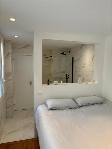 une chambre blanche avec un lit et un miroir dans l'établissement Appartement design avec terrasse, à Boulogne-Billancourt