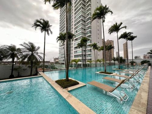 a swimming pool with lounge chairs and palm trees on a building at Ed. Mandarim in Curro Velho